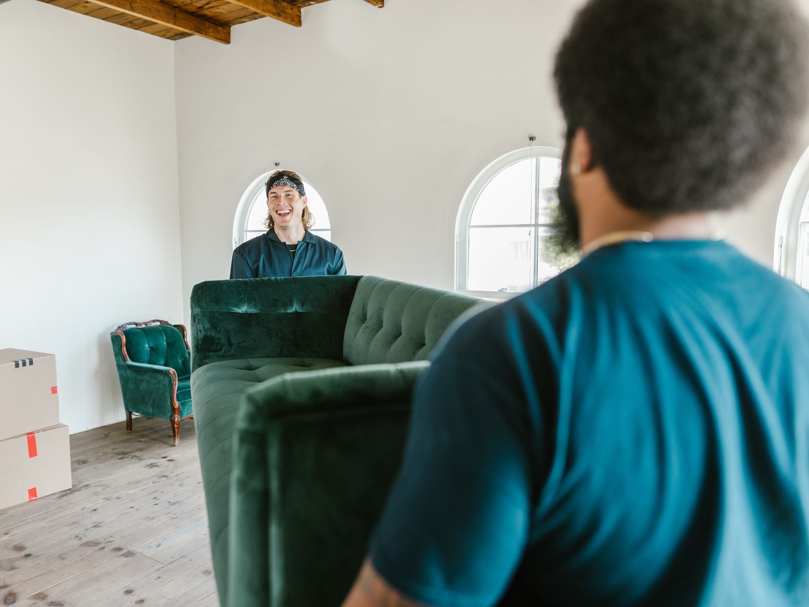 Zwei Mitarbeiter tragen gemeinsam ein Sofa aus einer Wohnung
