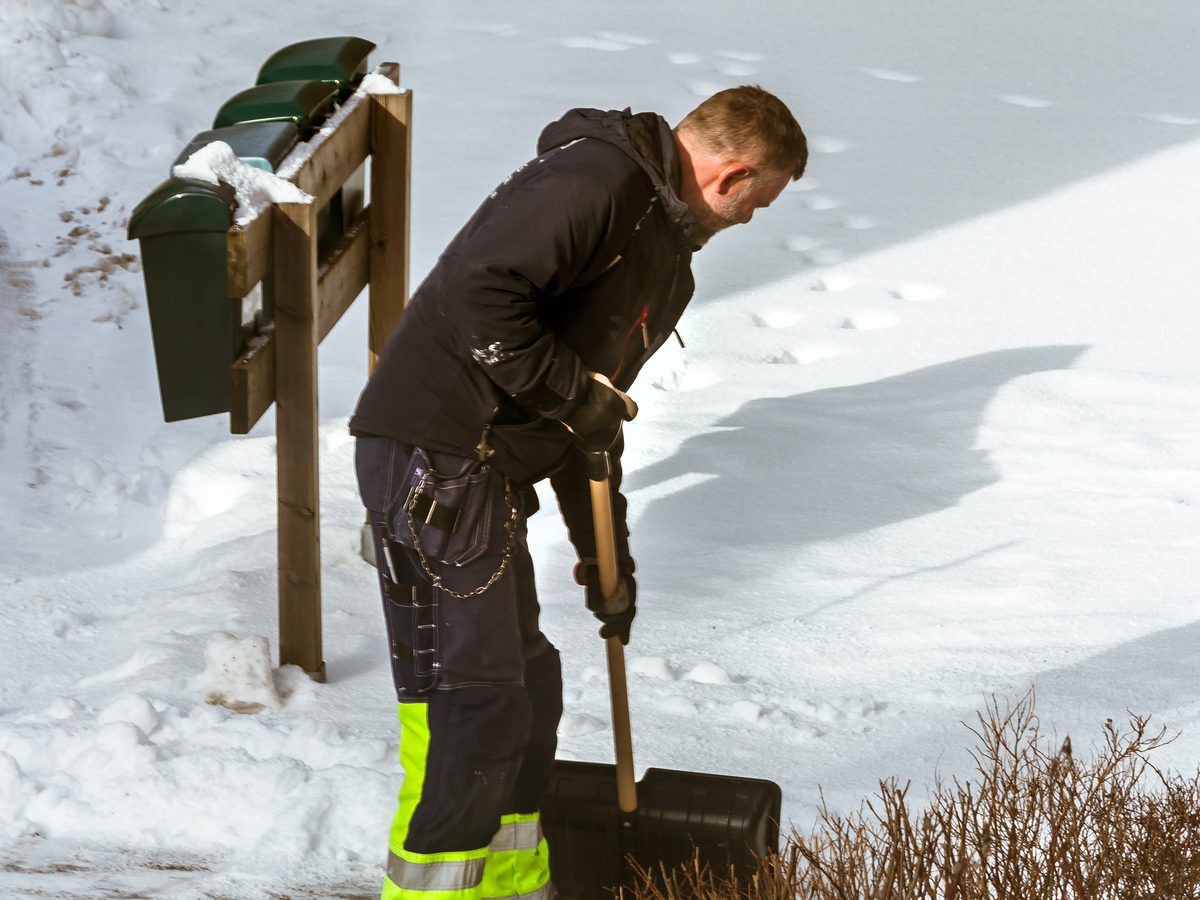 Winterdienst: Reinigungskraft beim Schneeräumen mit Schaufel